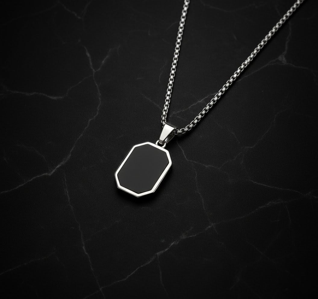 Silver necklace with a black hexagonal pendant on a dark textured background