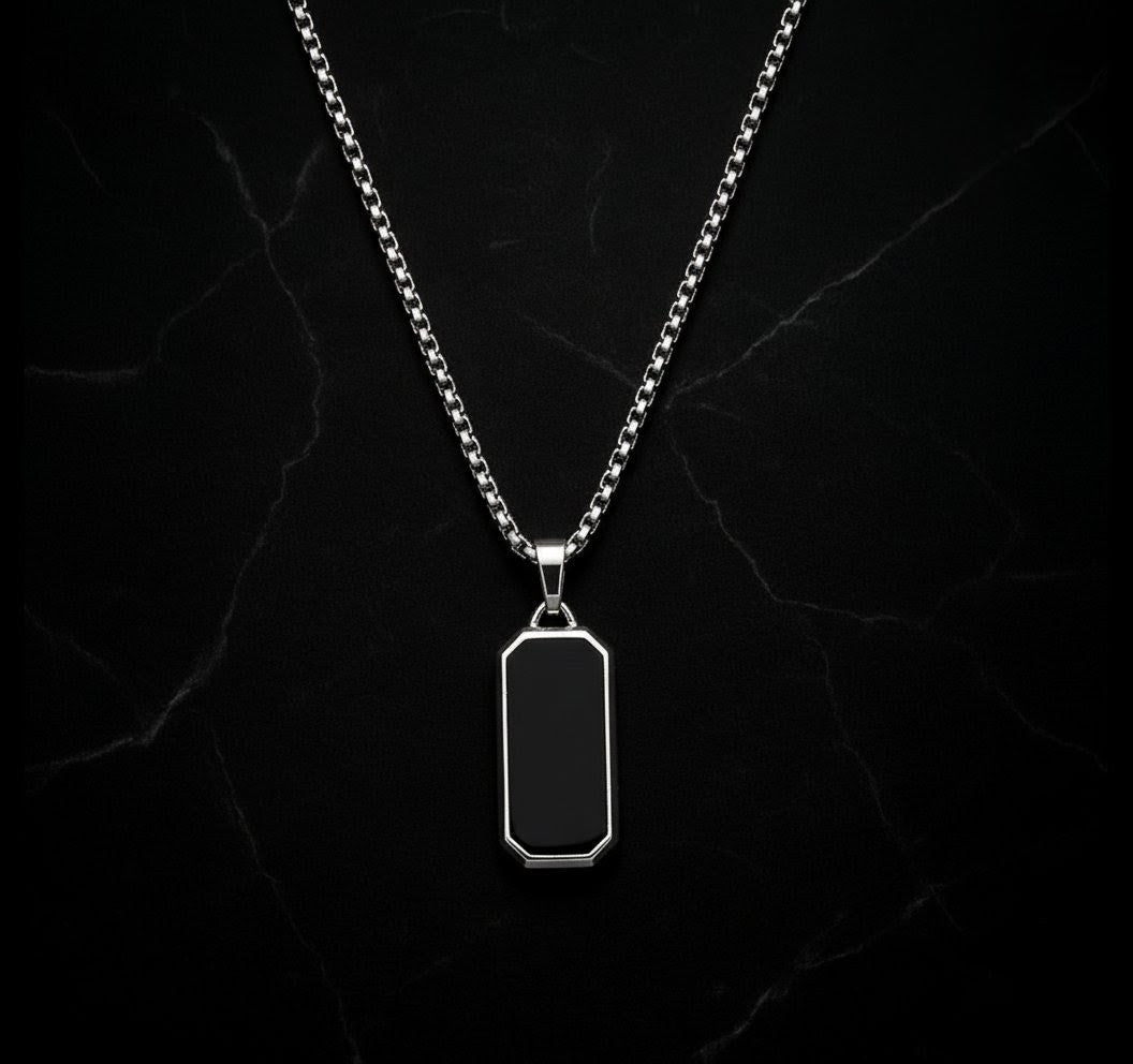 Silver necklace with a black pendant on a dark marble background