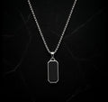 Silver necklace with a black pendant on a dark marble background