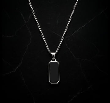 Silver necklace with a black pendant on a dark marble background
