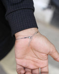 Hand wearing a silver bracelet with a blurred background