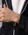 Person wearing a silver bracelet on their wrist with a blurred background