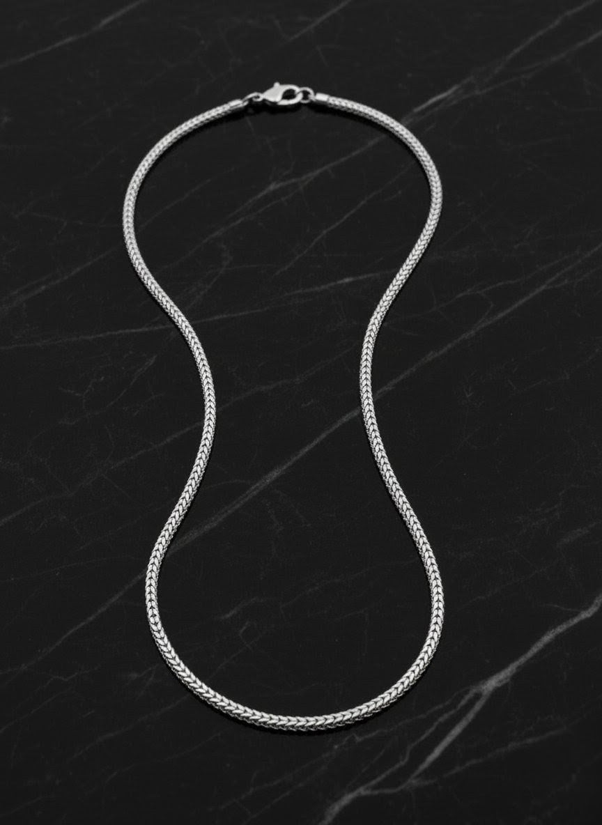 Silver chain necklace on a dark marble surface