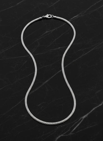 Silver chain necklace on a dark marble surface
