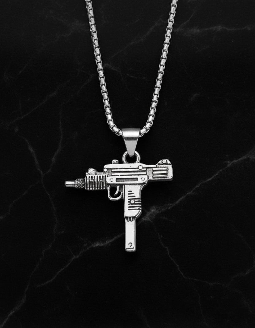 Silver gun-shaped pendant on a chain against a dark marble background