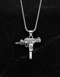 Silver gun-shaped pendant on a chain against a dark marble background