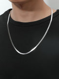 Silver necklace worn by a person on a plain background