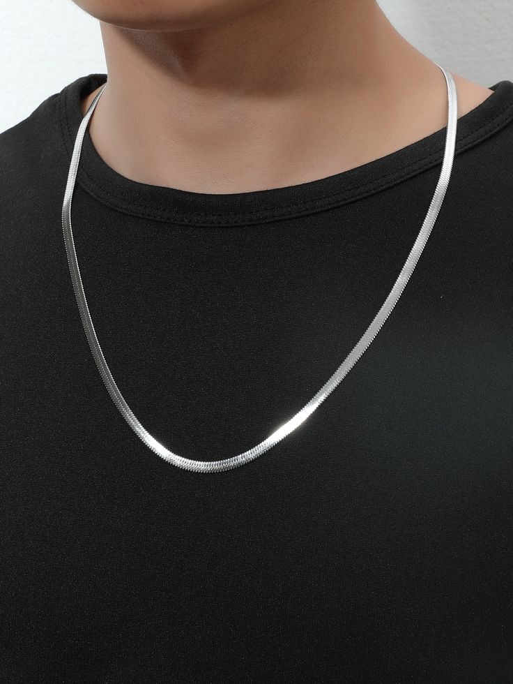Silver necklace worn by a person on a plain background