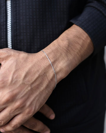 Close-up of a person's wrist wearing a silver bracelet with a dark jacket background