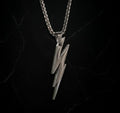 Silver lightning bolt pendant on a black chain against a black background