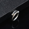 Silver ring with braided design on a black textured surface