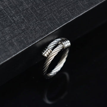 Silver ring with braided design on a black textured surface